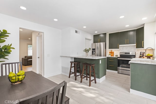 kitchen featuring light stone countertops, sink, a breakfast bar area, decorative backsplash, and appliances with stainless steel finishes