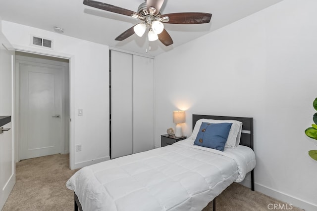 bedroom with ceiling fan, light colored carpet, and a closet