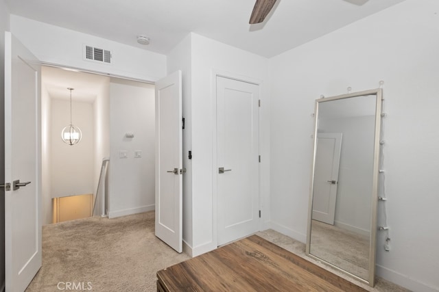 interior space with carpet floors and ceiling fan with notable chandelier