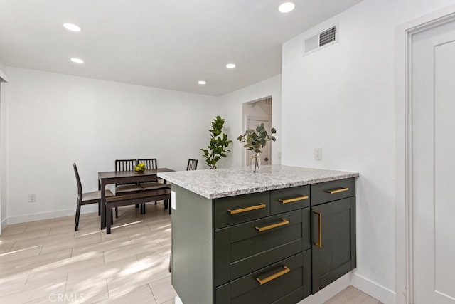 kitchen featuring kitchen peninsula and light stone counters