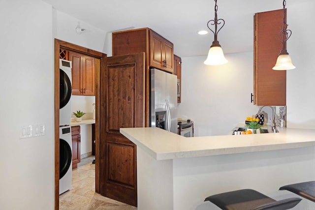 kitchen with stainless steel appliances, sink, pendant lighting, stacked washer / dryer, and a breakfast bar area