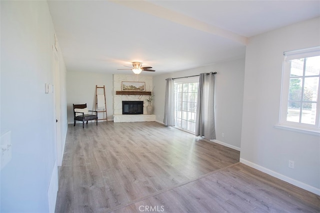 unfurnished living room with ceiling fan, light hardwood / wood-style floors, and a fireplace