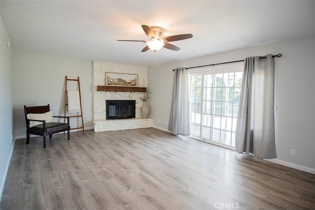 living room featuring ceiling fan, a fireplace, and light hardwood / wood-style flooring