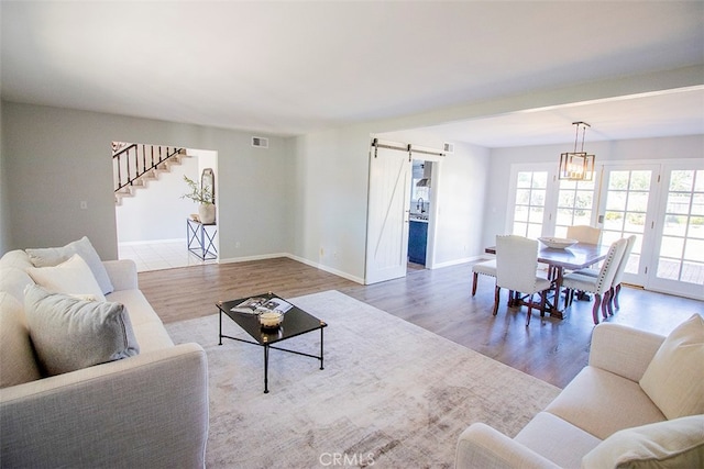 living room with a barn door, light hardwood / wood-style floors, and a chandelier