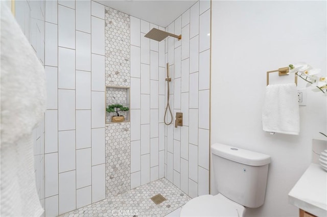 bathroom with vanity, toilet, and tiled shower