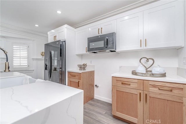 kitchen with stainless steel refrigerator with ice dispenser, ornamental molding, light brown cabinets, and white cabinets