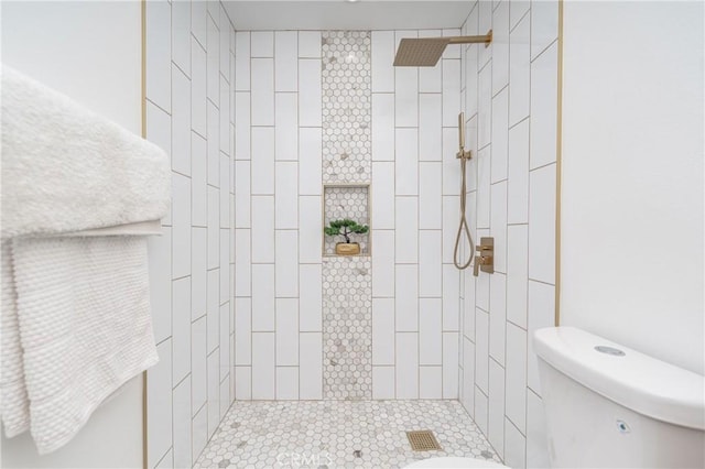 bathroom with a tile shower and toilet