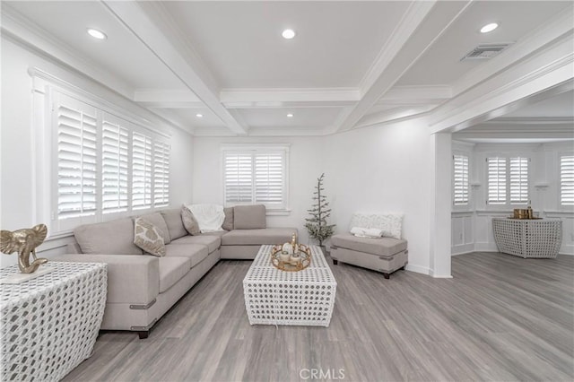 living room with a healthy amount of sunlight, beam ceiling, and light hardwood / wood-style flooring