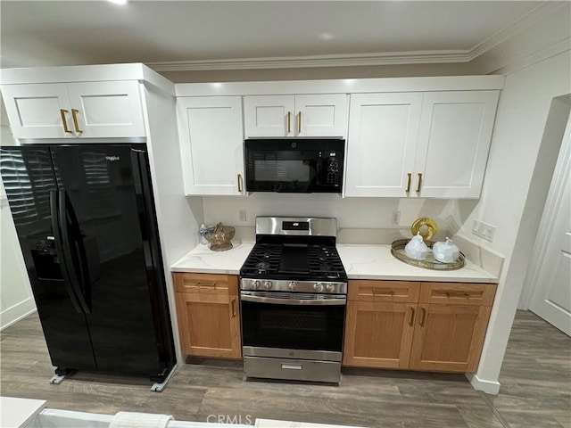 kitchen with ornamental molding, white cabinets, light stone counters, and black appliances