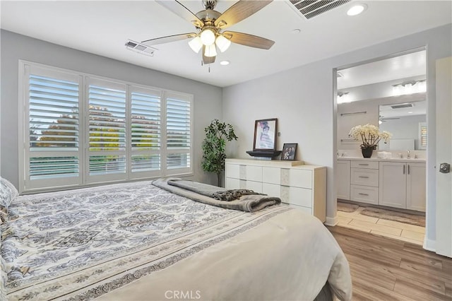 bedroom with ensuite bath, sink, ceiling fan, and light hardwood / wood-style flooring