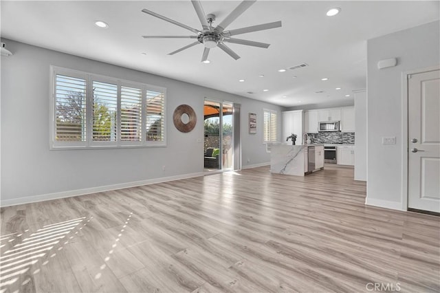 unfurnished living room with ceiling fan and light wood-type flooring