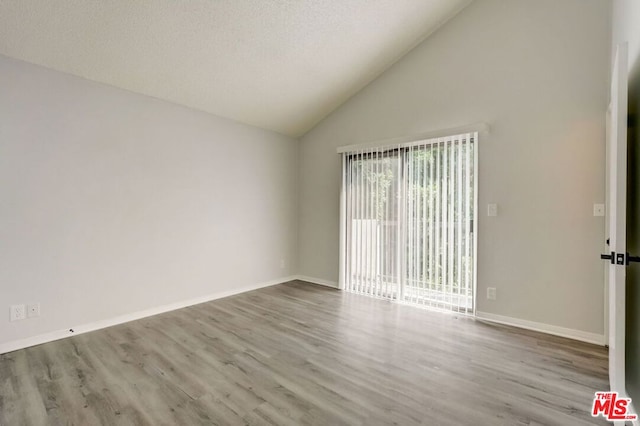 empty room featuring a textured ceiling, high vaulted ceiling, and light hardwood / wood-style flooring