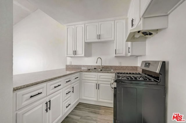 kitchen with white cabinets, sink, light hardwood / wood-style flooring, stainless steel gas range, and light stone countertops