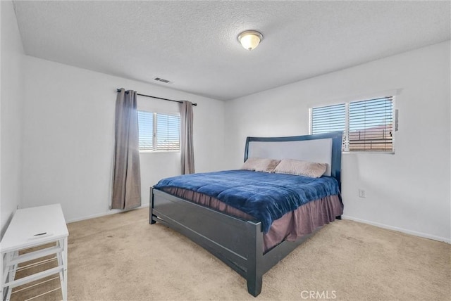 bedroom featuring light colored carpet and a textured ceiling