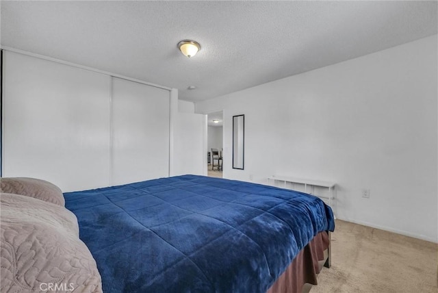 bedroom with carpet flooring, a textured ceiling, and a closet