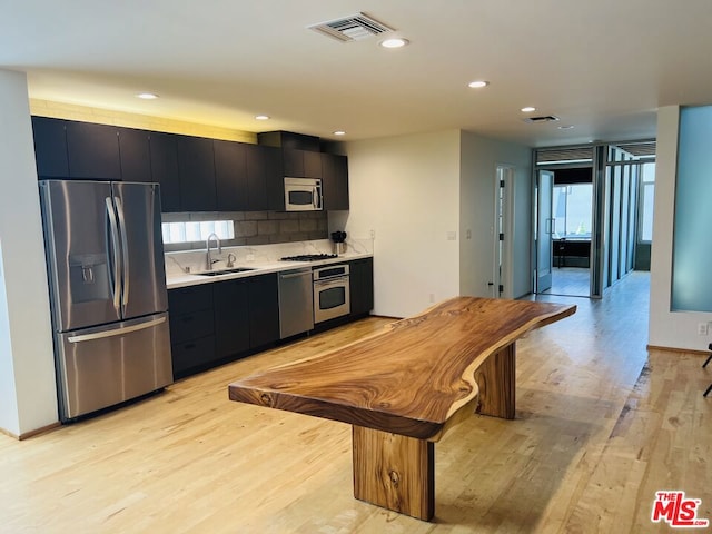 kitchen with decorative backsplash, appliances with stainless steel finishes, light hardwood / wood-style flooring, and sink