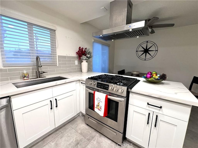 kitchen with kitchen peninsula, sink, island exhaust hood, white cabinetry, and appliances with stainless steel finishes