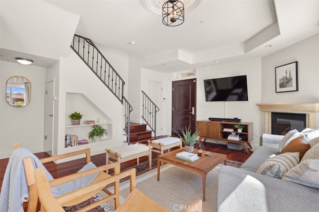 living room featuring a raised ceiling, hardwood / wood-style floors, and a chandelier