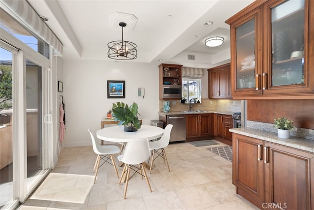 dining area featuring a tray ceiling, sink, light tile patterned floors, and a chandelier