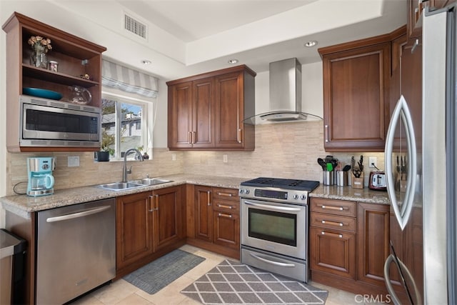 kitchen with sink, wall chimney exhaust hood, decorative backsplash, light stone counters, and stainless steel appliances