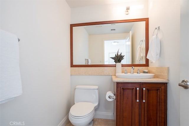 bathroom with toilet, vanity, and tile patterned floors