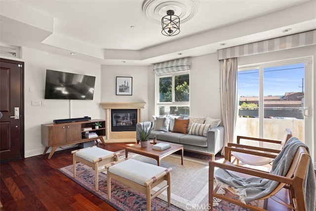 living room with dark hardwood / wood-style floors, a healthy amount of sunlight, and a tray ceiling