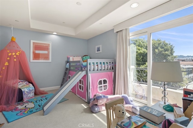 bedroom with carpet floors, a tray ceiling, and multiple windows