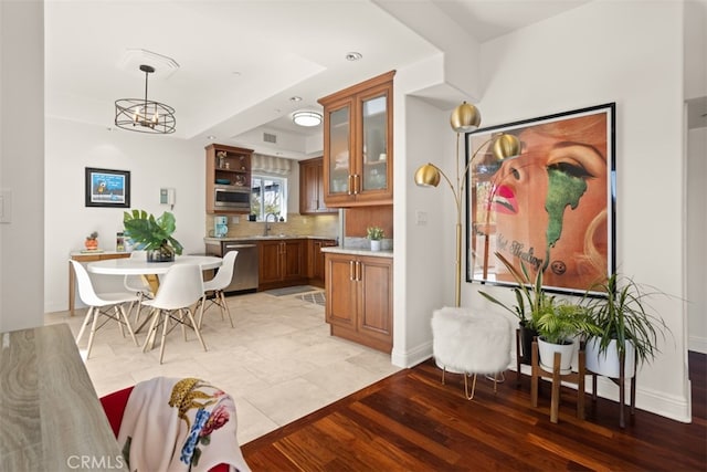 kitchen featuring sink, tasteful backsplash, pendant lighting, light hardwood / wood-style floors, and appliances with stainless steel finishes