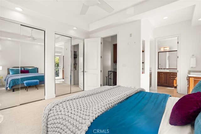 carpeted bedroom with connected bathroom, ceiling fan, and multiple closets