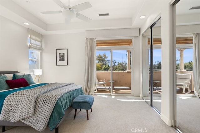 carpeted bedroom with a tray ceiling, ceiling fan, and a closet