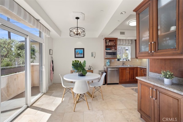 dining area with light tile patterned flooring, a raised ceiling, sink, and an inviting chandelier