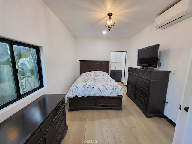 bedroom featuring a wall mounted AC and light hardwood / wood-style floors