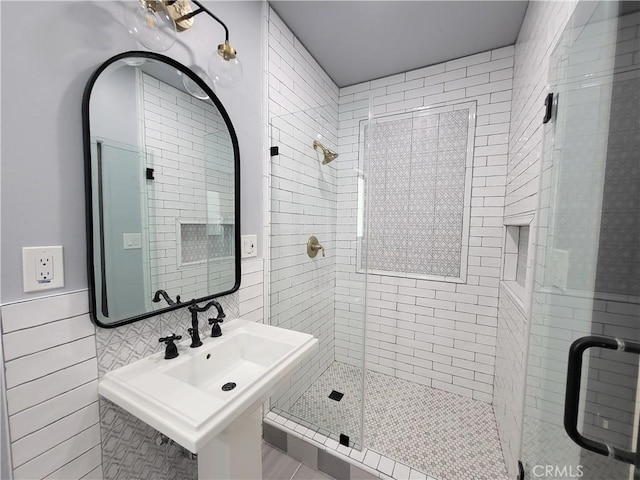 bathroom featuring sink, a shower with shower door, and tile walls