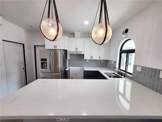 kitchen featuring sink, hanging light fixtures, stainless steel fridge with ice dispenser, decorative backsplash, and white cabinetry