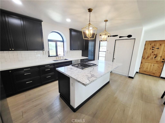 kitchen featuring tasteful backsplash, sink, decorative light fixtures, light hardwood / wood-style floors, and a kitchen island