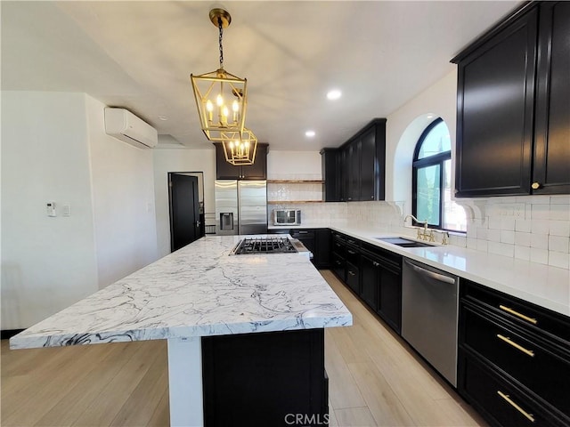 kitchen featuring a wall mounted air conditioner, appliances with stainless steel finishes, light wood-type flooring, sink, and a center island