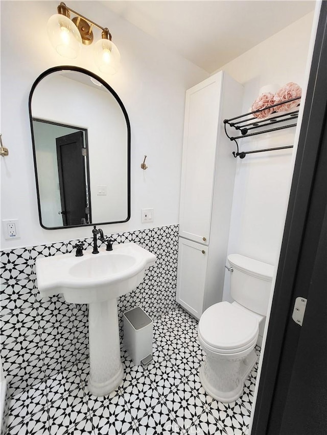 bathroom featuring tile patterned floors, toilet, and tile walls