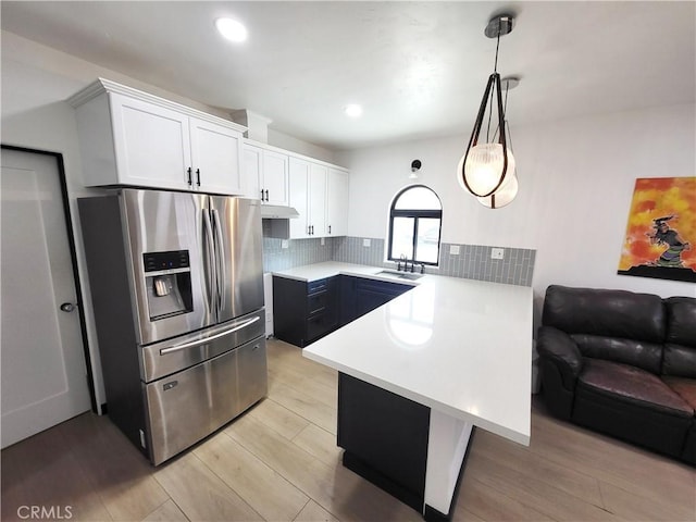 kitchen featuring kitchen peninsula, stainless steel refrigerator with ice dispenser, pendant lighting, white cabinets, and light hardwood / wood-style floors