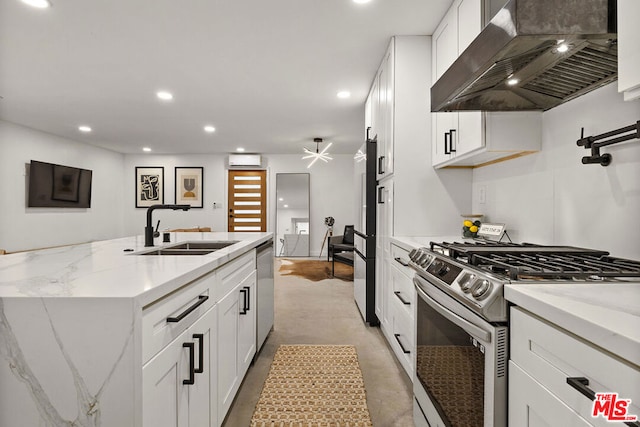 kitchen with white cabinets, sink, wall chimney exhaust hood, light stone countertops, and appliances with stainless steel finishes