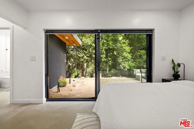 bedroom with concrete flooring, ensuite bath, and multiple windows