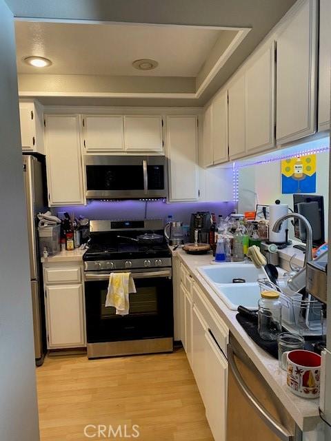 kitchen featuring sink, stainless steel appliances, white cabinetry, and light hardwood / wood-style flooring