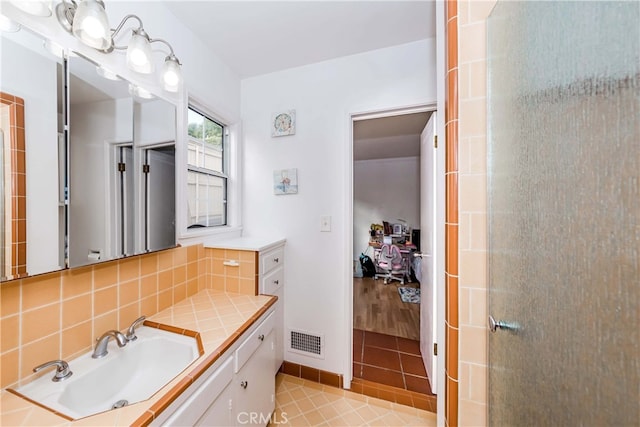 bathroom featuring tile patterned floors, vanity, a shower with door, and tasteful backsplash