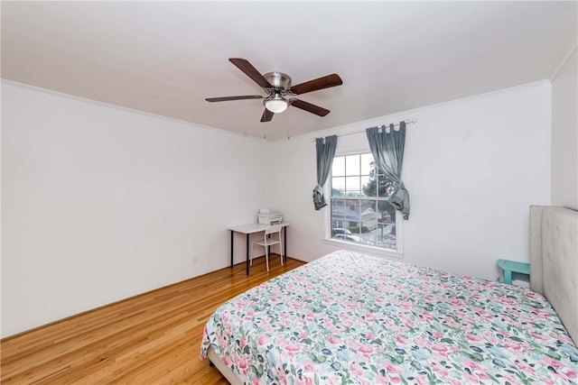 bedroom with ceiling fan, ornamental molding, and hardwood / wood-style flooring