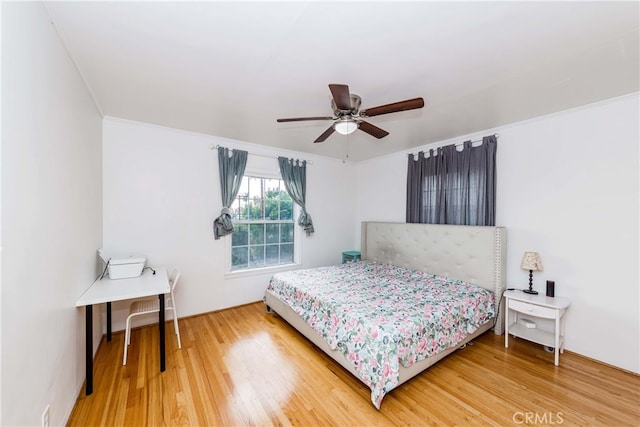 bedroom with hardwood / wood-style flooring, ceiling fan, and ornamental molding