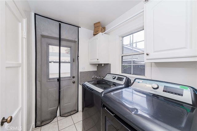 laundry area featuring a healthy amount of sunlight, washer and clothes dryer, light tile patterned floors, and cabinets