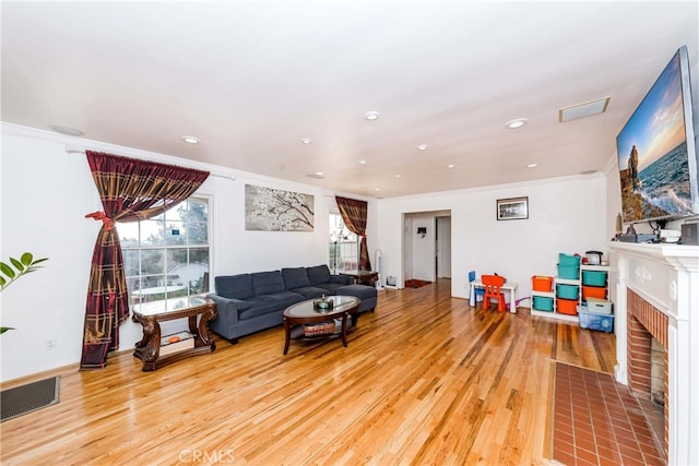 living room with light hardwood / wood-style floors, crown molding, and a fireplace