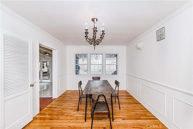 dining area with ornamental molding, light hardwood / wood-style floors, and a notable chandelier