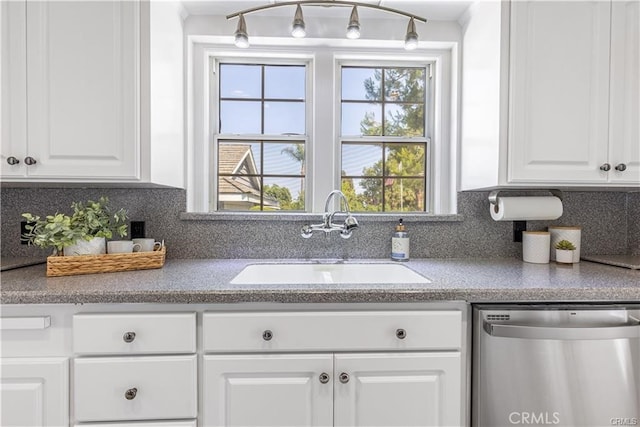 kitchen featuring stainless steel dishwasher, backsplash, white cabinetry, and sink