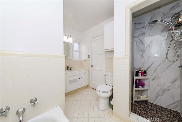 bathroom with tile patterned flooring, vanity, toilet, and tile walls