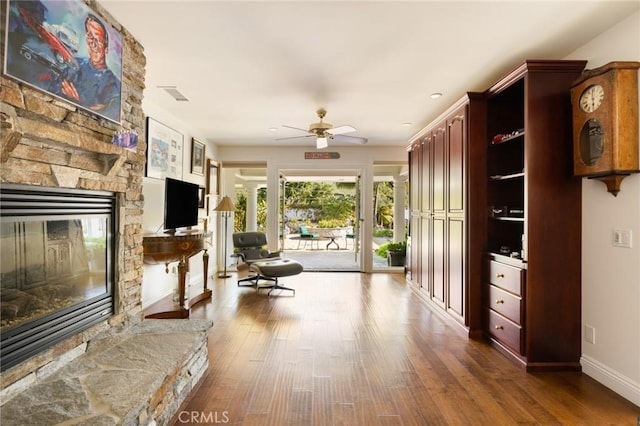 interior space with hardwood / wood-style floors, ceiling fan, and a stone fireplace